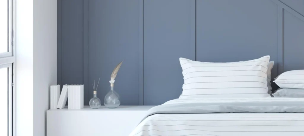 A Minimalist bedroom interior Rendering featuring a blue accent wall, white bedding, and decorative vases