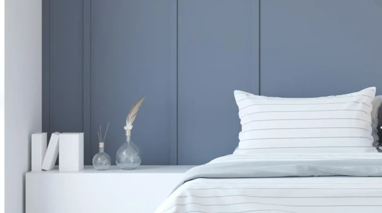 A Minimalist bedroom interior Rendering featuring a blue accent wall, white bedding, and decorative vases