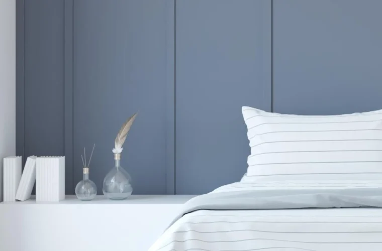 A Minimalist bedroom interior Rendering featuring a blue accent wall, white bedding, and decorative vases